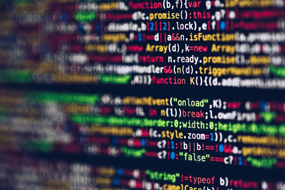 A close-up of a computer screen displaying lines of source code with syntax highlighting in various colors including red, green, blue, yellow, and white. The code appears slightly blurred, making indi